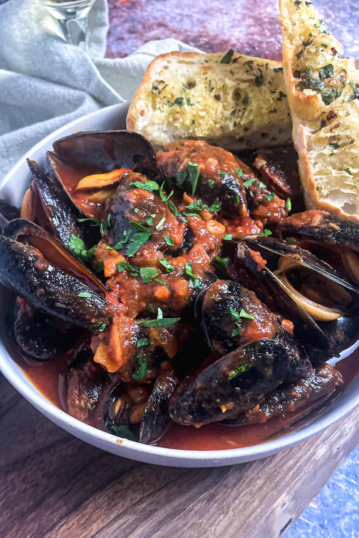mussels in tomato sauce in a bowl with garlic bread