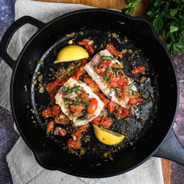 tuscan cod with capers and tomatoes in a cast iron pan