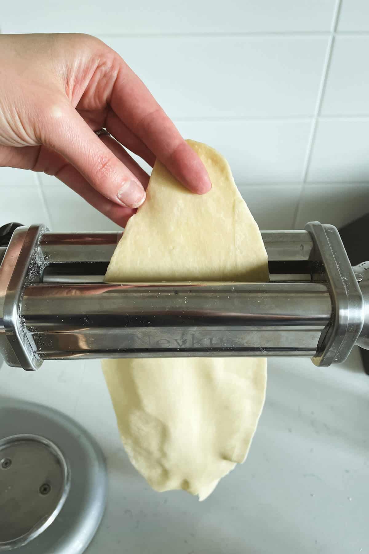 rolling pasta dough through machine