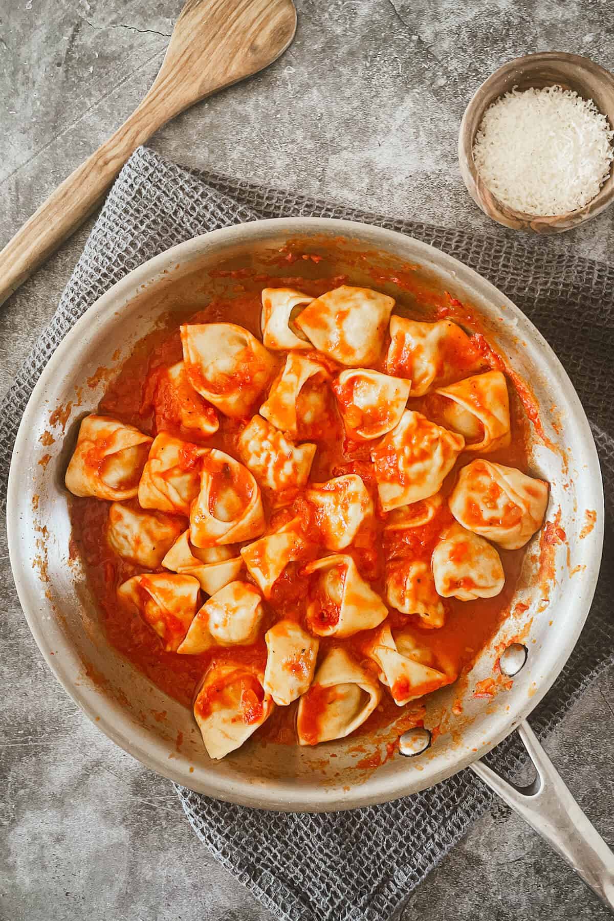 sausage and kale tortellini in a pan with tomato sauce