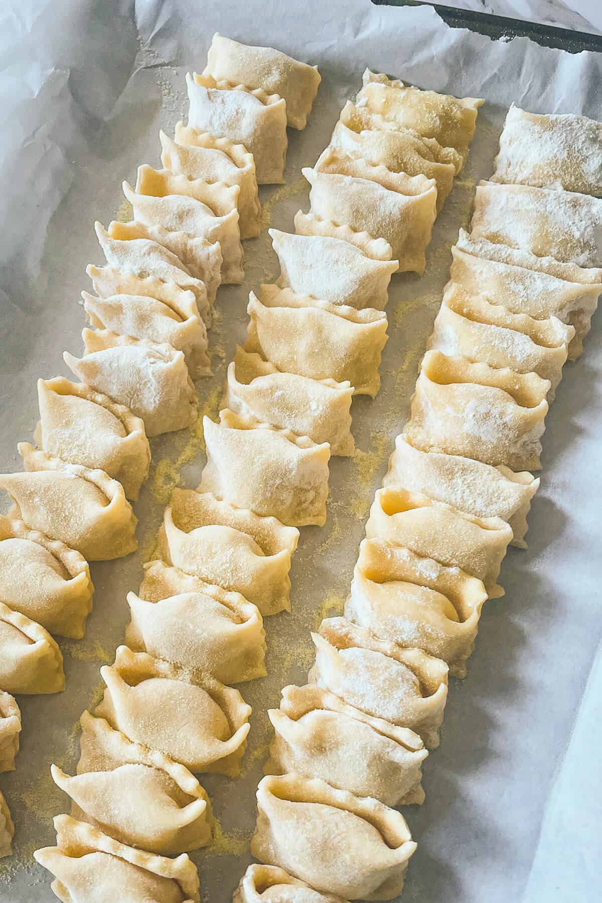 rows of uncooked agnolotti on a pan
